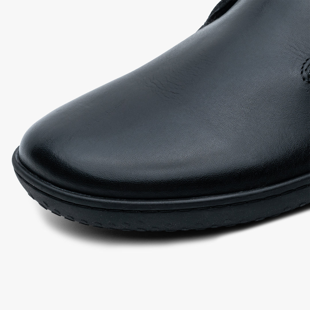 Nærbillede af Vivobarefoot Gobi Lux i varianten Obsidian, fremviser den glatte sorte læderoverdel og fleksible sål, ideel for naturlig fodbevægelse.