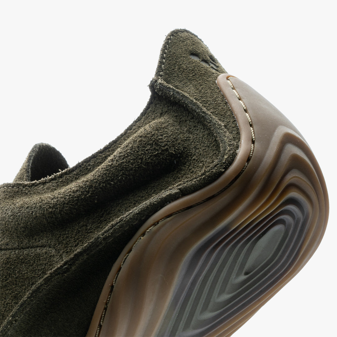 Nærbillede af Vivobarefoot Sensus Mens i varianten Olive, viser den robuste hældel og detaljeret vildthudslæder med præcis syning. Billedet fremviser også den tynne, fleksible sål.